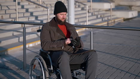 man in wheelchair using smartphone outside