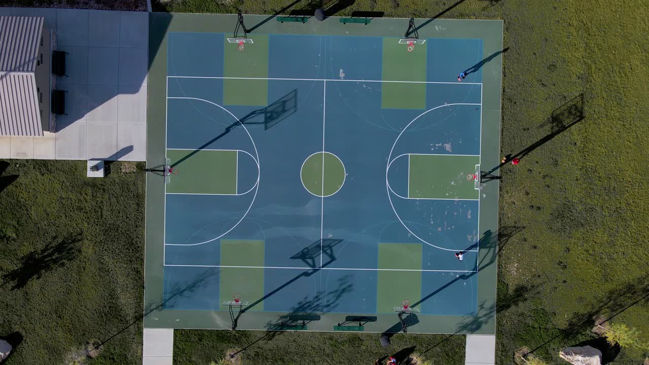 Vista dall'alto di un campo da basket con un uomo che gioca e palleggia in una giornata di sole