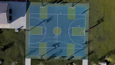 top view of a basketball court with a man playing and dribbling ball on a sunny day