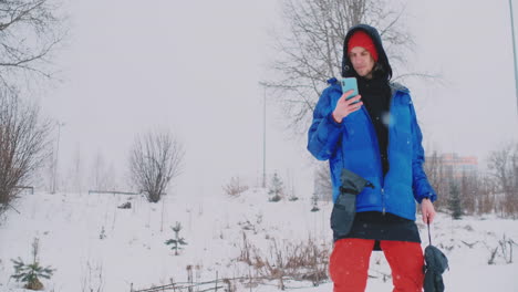 Slow-motion-shot-of-a-snowboarder-using-a-smartphone-while-driving-on-a-ski-slope