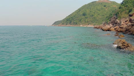 Movimiento-Bajo-Sobre-El-Agua-Azul-Perfecta-Del-Océano-Junto-A-La-Isla-Verde