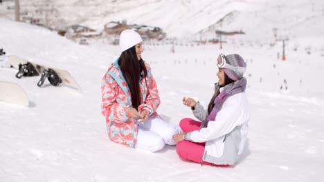 Two-young-female-friends-chatting-in-the-snow