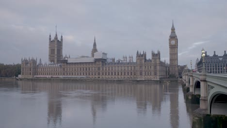 Wide-shot-of-the-London-Parliament-building-in-its-full-glory,-with-the-river-Thames-in-the-foreground-and-cars-on-the-bridge