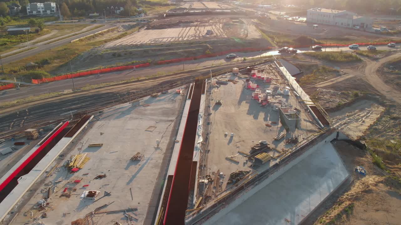 Aerial fly over highway interchange construction site at sunset with cars passing by