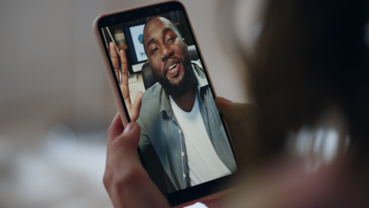 Kvinde videochatter på smartphone med online forretningspartner i hjemmet – nærbillede