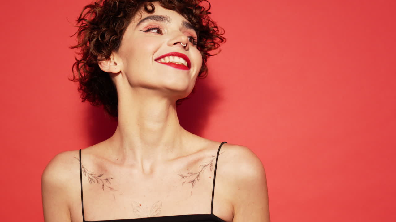 mujer sonriente con cabello rizado y tatuajes
