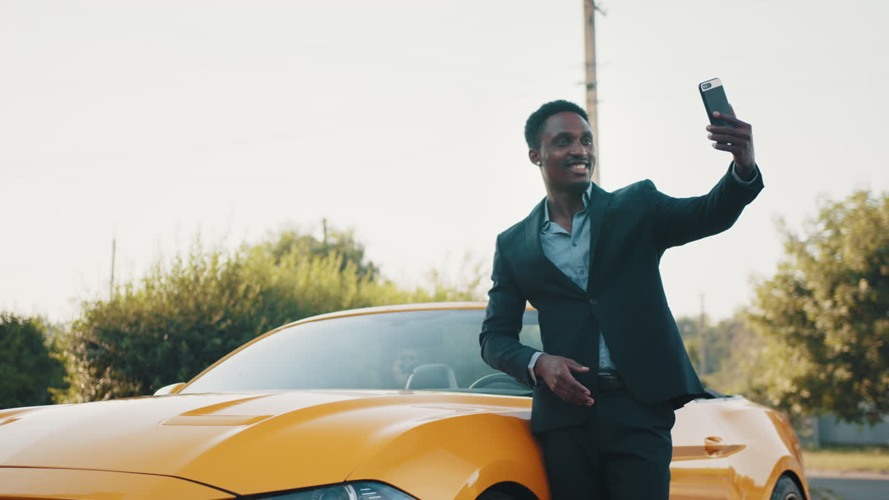 hombre tomando una selfie al lado de un coche descapotable amarillo