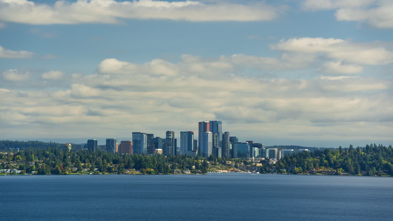 Time lapse of Bellevue skyline with sailboats in the distance, yachts in the foreground, and modern skyscrapers under a dynamic cloud movement