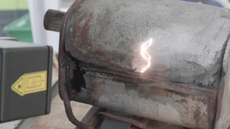 cleaning old rusty exhaust with laser cleaning device, burning off rust with visible laser beam while generating smoke