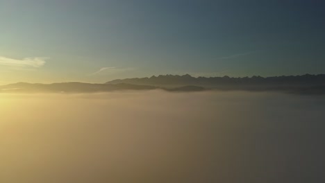 aerial above mist during colorful sunrise with mountain peaks in distance