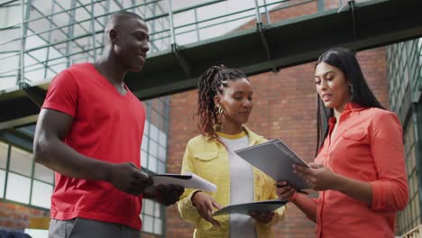 Happy-diverse-female-and-male-business-colleagues-discussing-work-at-meeting