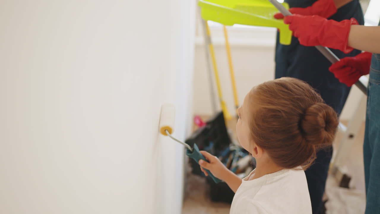 Child Painting a Wall with Family