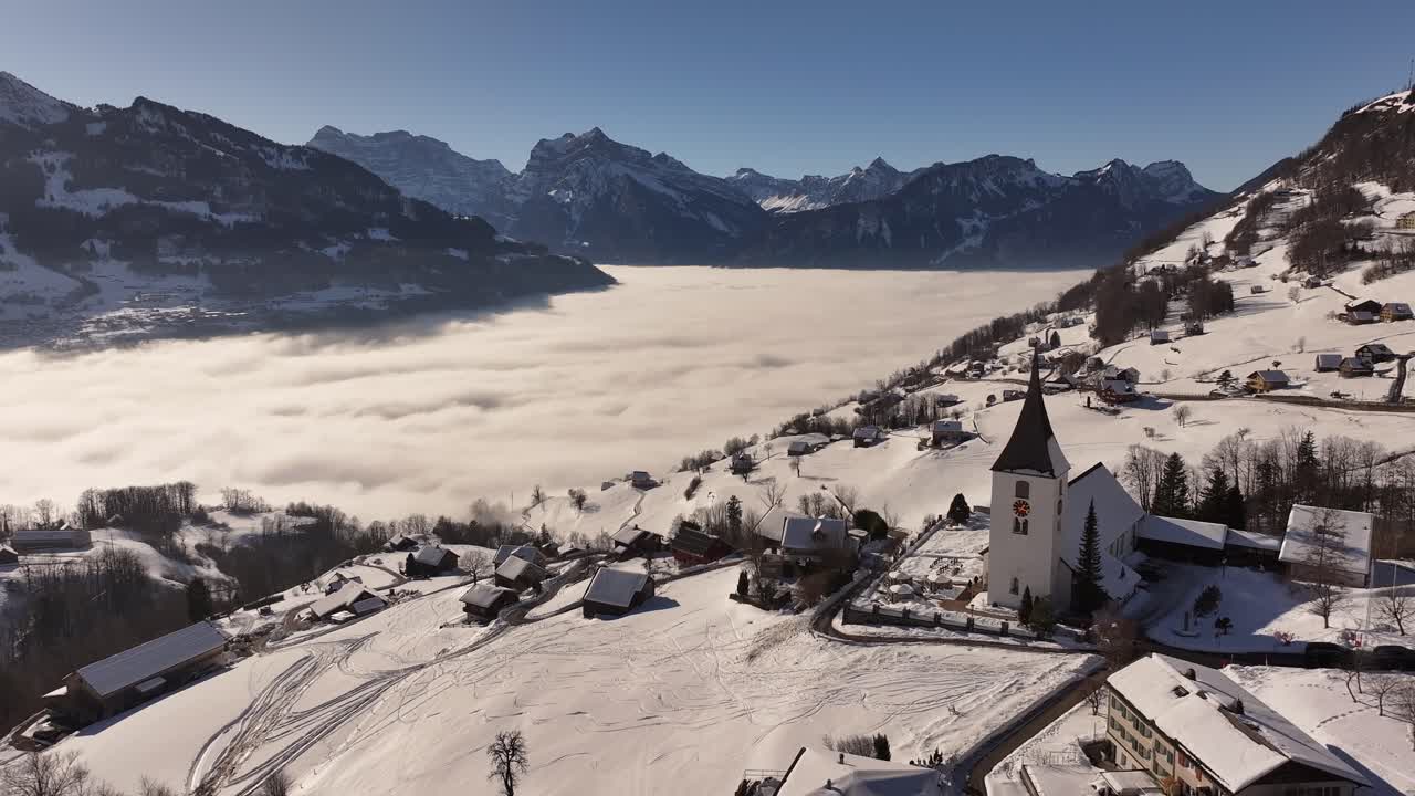 Breathtaking aerial view of Amden village, charming snow-covered church and stunning alpine scenery, Walensee in Swiss alps.
