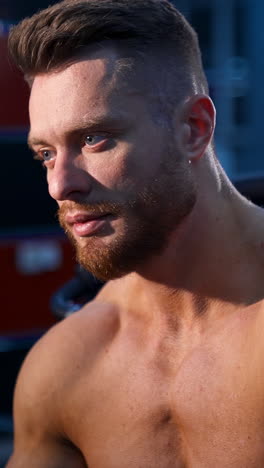 close-up portrait of a shirtless man with a beard and short hair.