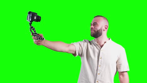 young smiling vlogger holding camera on tripod and filming video