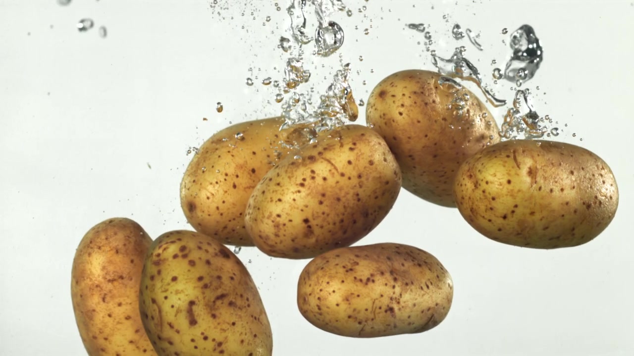 Patate fresche che cadono in acqua limpida con bolle