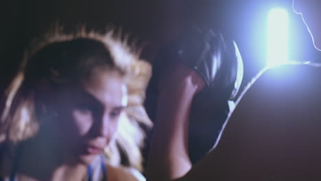 medium shot of beautiful fitness woman boxer treneruemsya strike speed focus mitts with a coach in a boxing club. slow motion