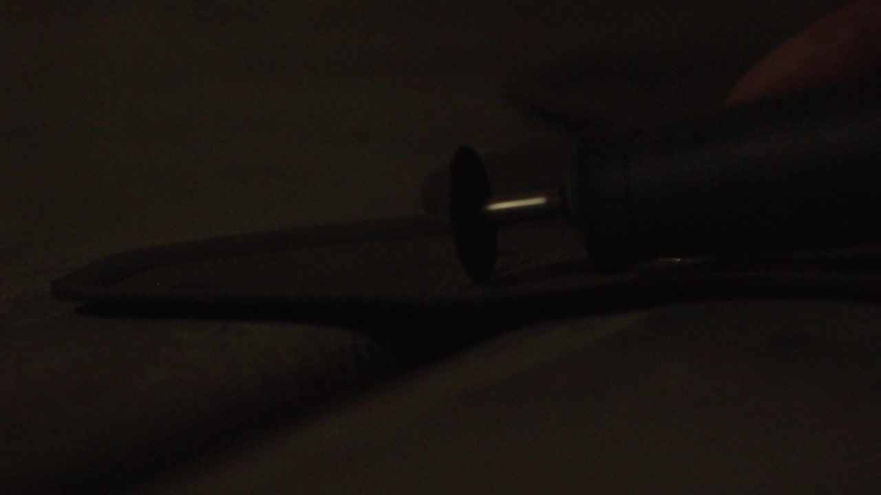 A small rotary tool cuts through a metal frame with sparks flying.
