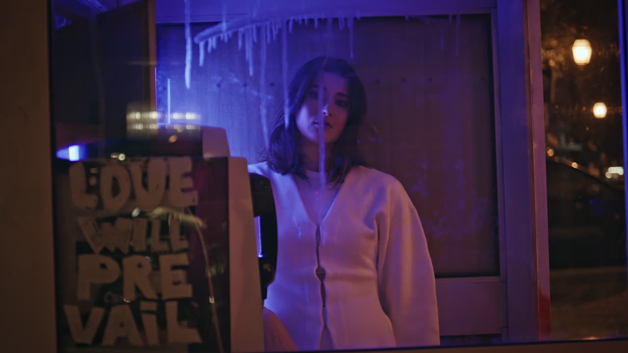 Sad model calling telephone in neon light closeup. Girl picking down handset