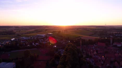 Drone-Aéreo-Vuela-Contra-La-Puesta-De-Sol-Hermoso-Panorama-Del-Casco-Antiguo-Campo-De-Fútbol-árboles-Parque-Verdes-Prados-Y-Campos-Destello-De-Lente