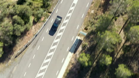 Aerial-view-top-down-following-BMW-moving-fast-along-bright-sunny-freeway-during-daytime