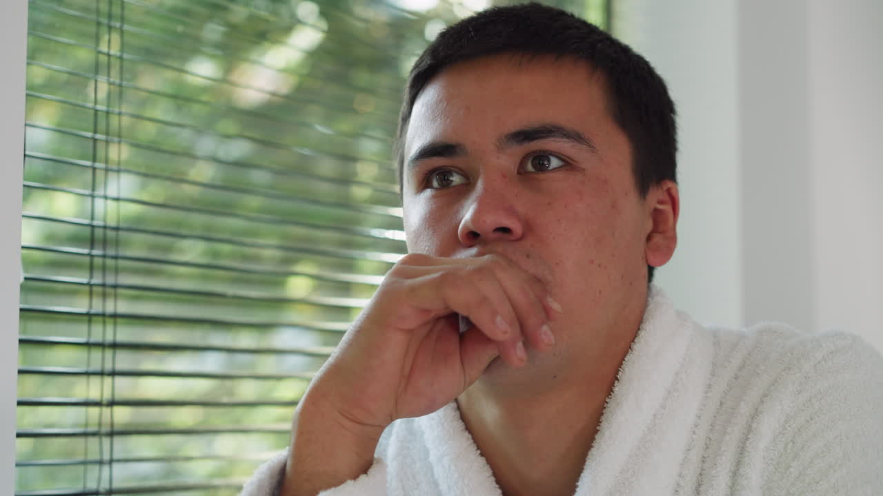 창문 에 앉아 있는 남자가 생각하고 있다. - 테리 욕조를 입은 사려 깊은 남자가 아침에 집에서 휴식을 취한다. - 예쁜 젊은이가 주말에 자유 시간을 즐긴다.