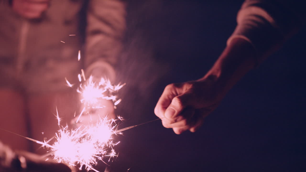 amigos en la playa con chispas celebrando al atardecer