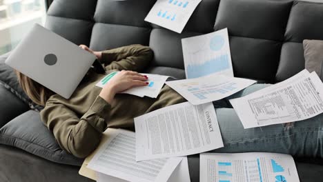 woman overwhelmed by work and documents, lying on couch