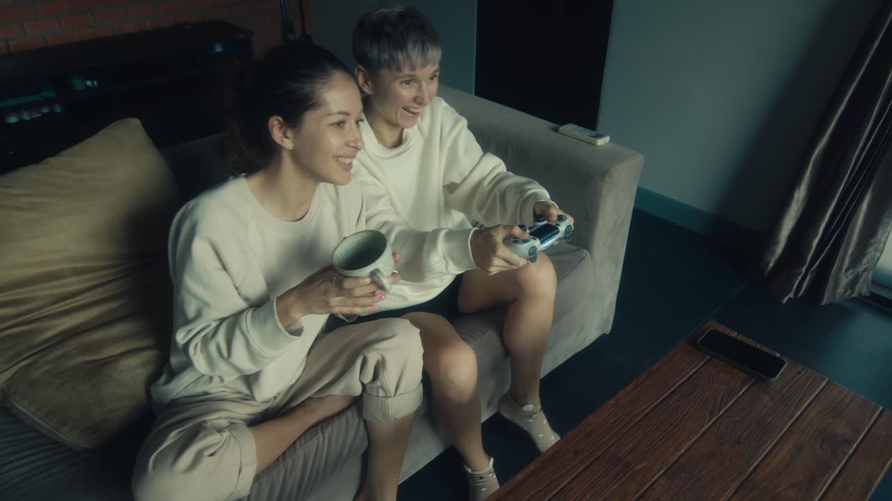 Two women playing video games on a couch
