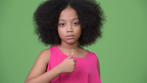 アフロの可愛い若いアフリカの女の子が 親指を上げている