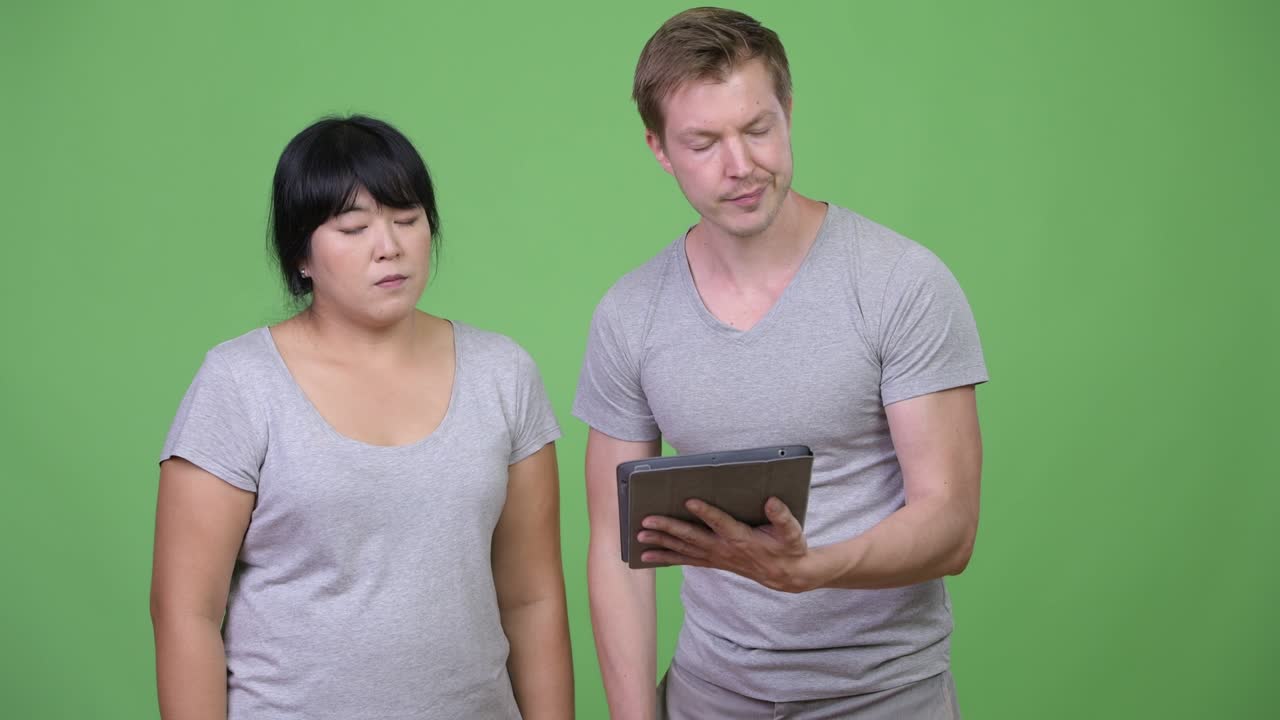 Young multi-ethnic couple using digital tablet and getting bad news together