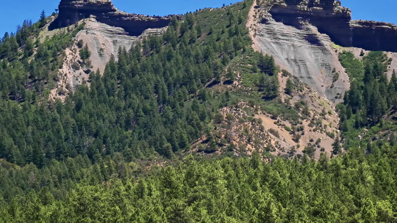 Toma aérea cinematográfica de dron de 70 mm de Chimney Rock cerca de Owl Creek Pass en el Bosque Nacional Uncompahgre, cerca de Pagosa Springs, Colorado, enmarcado por un terreno alpino accidentado y picos irregulares.
