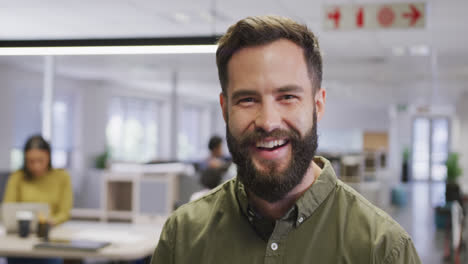 Portrait-of-happy-caucasian-businessman-over-business-colleagues-in-office