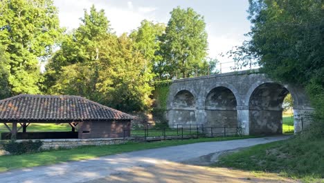 viaducto ferroviario con vieja casa de lavado francesa en el frente con árboles