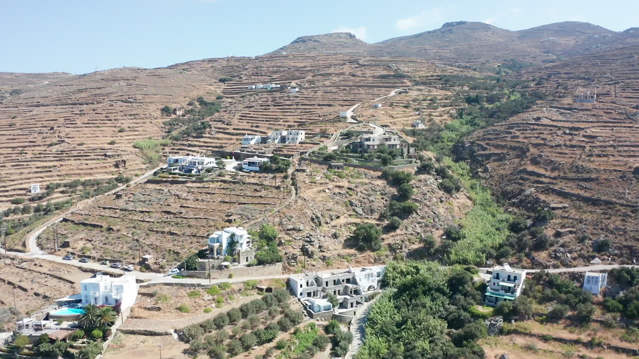 vuelo aéreo de drones hacia el paisaje montañoso seco con pocas casas ubicadas en la colina en tinos, grecia