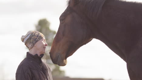 mujer emocional llorando con los ojos cerrados mientras está cerca del caballo, terapia de caballos