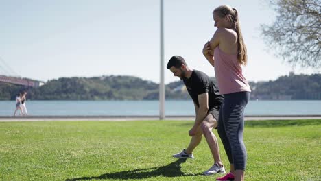 Side-view-of-sportsmen-warming-up-before-morning-workout-in-park.