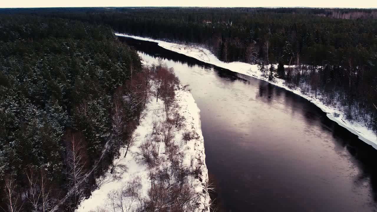En snoet flod nær en lille by med et skovmassiv.