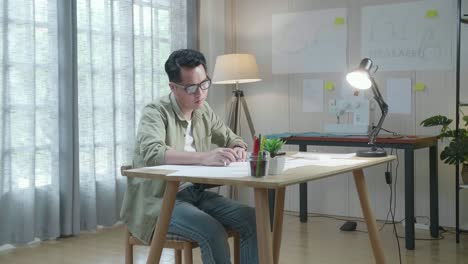 아시아인 디자이너가 사무실에서 레이아웃을 그리는 동안 재판을 받고 있습니다.