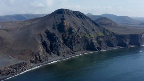 Drohnenblick-Auf-Die-Spektakuläre-Schwarze-Vulkanklippe-In-Island.-Draufsicht-Schwarze-Sandstrandküste-Mit-Krachenden-Ozeanwellen