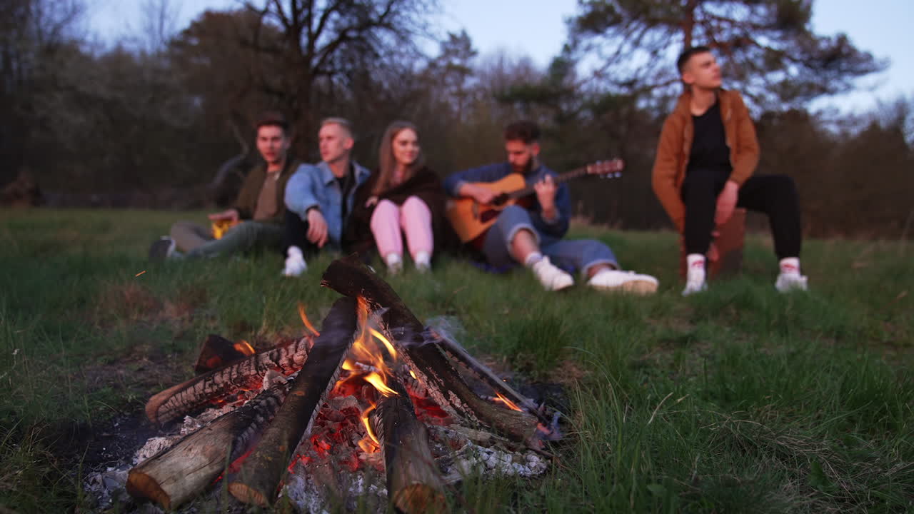 Friends enjoying a campfire and music in the woods