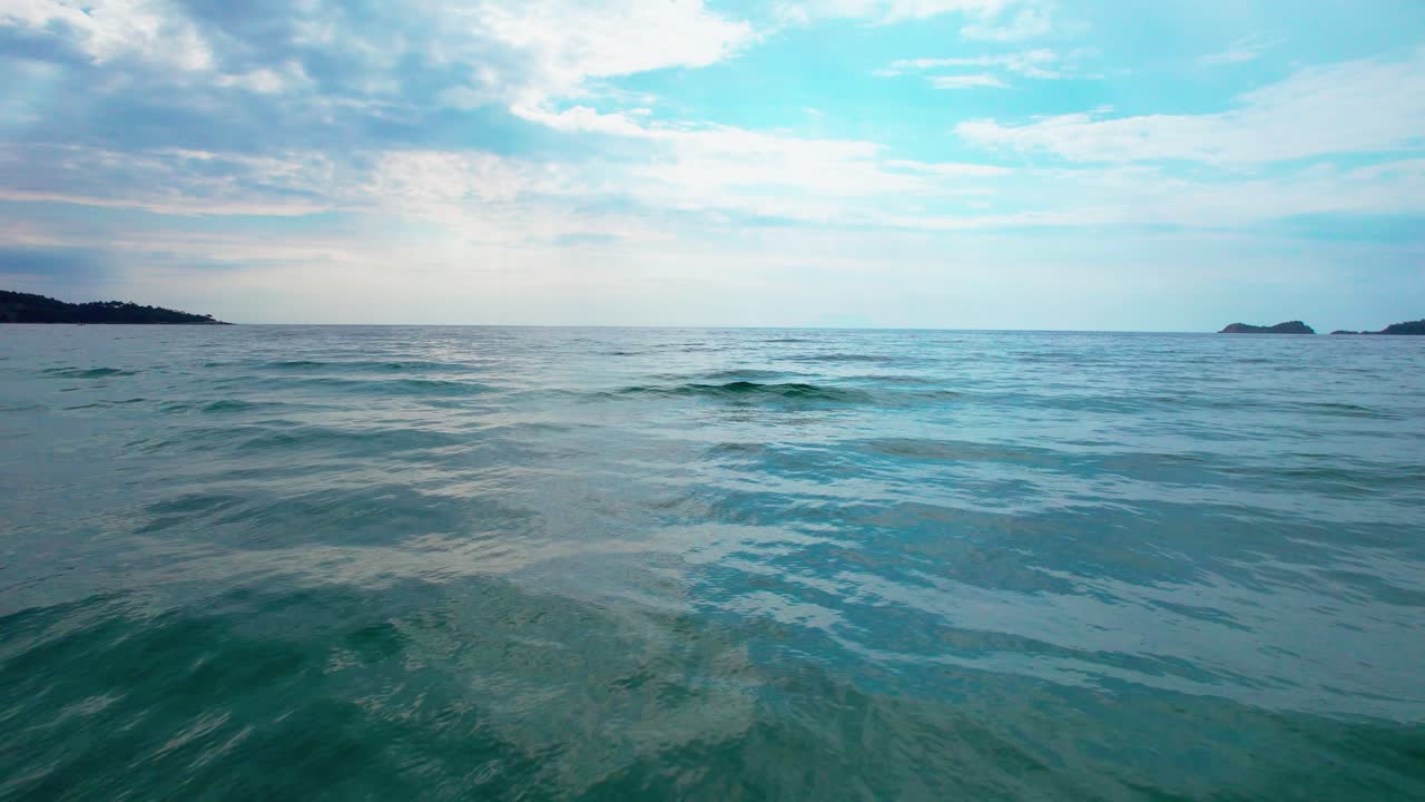 카메라는  ⁇ 은 파란 하늘과 배경의 작은 섬, 타소스 섬, 그리스, 유럽과 함께 바다 파도에 가까이 움직입니다.