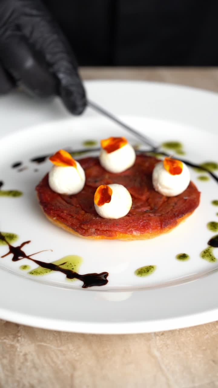 Kokk som dekorerer en gourmet-appetittvekker på en hvit tallerken