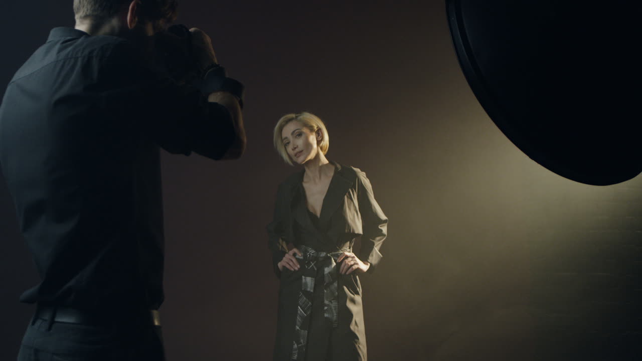 스튜디오에서 사진 작가의 카메라에 전문적으로 포즈를 취하는 젊은 아름다운 백인 여성 모델을 확대 및 축소하는 카메라