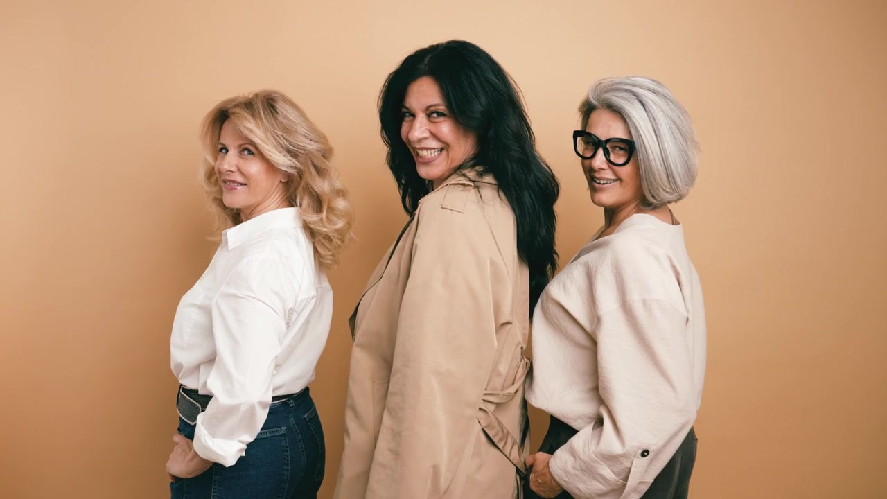 Tre donne mature diverse che si girano per sorridere alla fotocamera