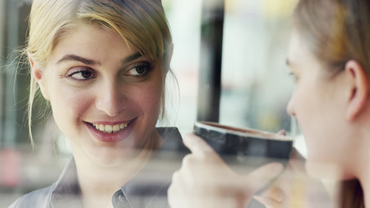 Due donne che usano un tablet digitale e bevono caffè in caffetteria
