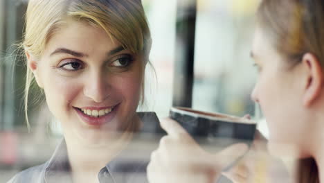 Zwei-Frauen-Nutzen-Ein-Digitales-Tablet-Und-Trinken-Kaffee-Im-Café