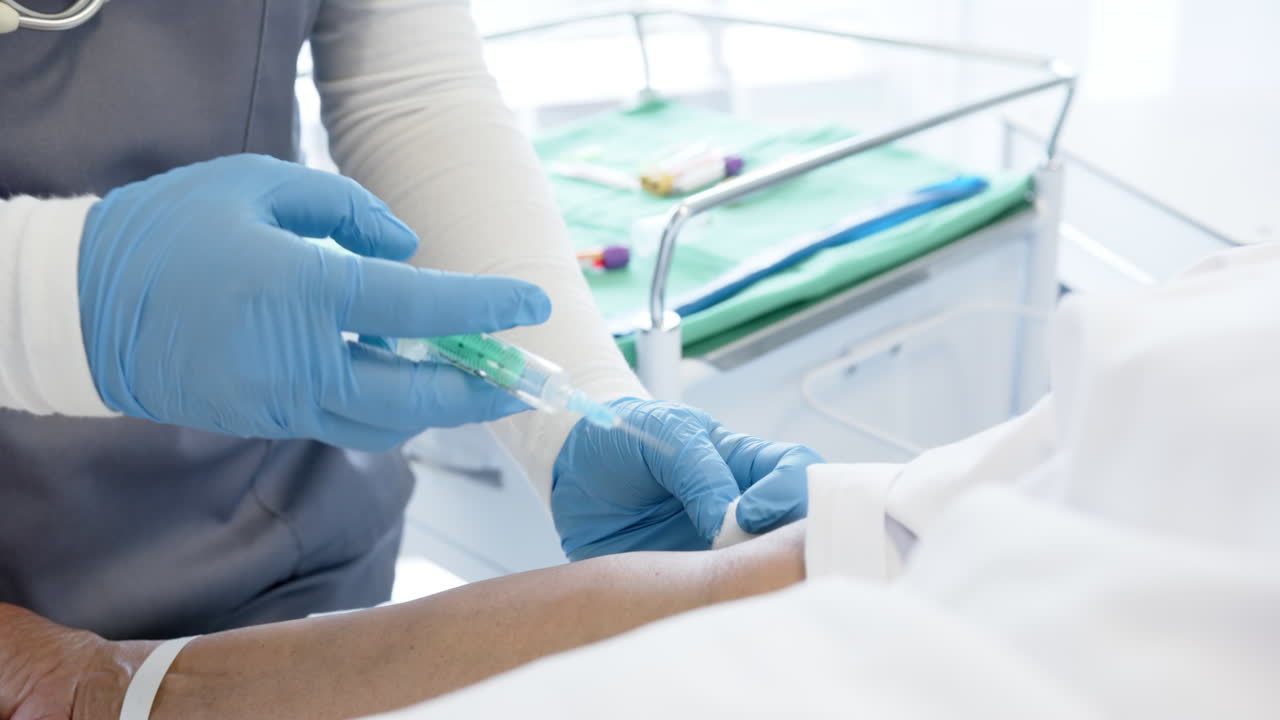 mujer médica diversa dando una inyección a una paciente de edad avanzada en una habitación del hospital, en cámara lenta