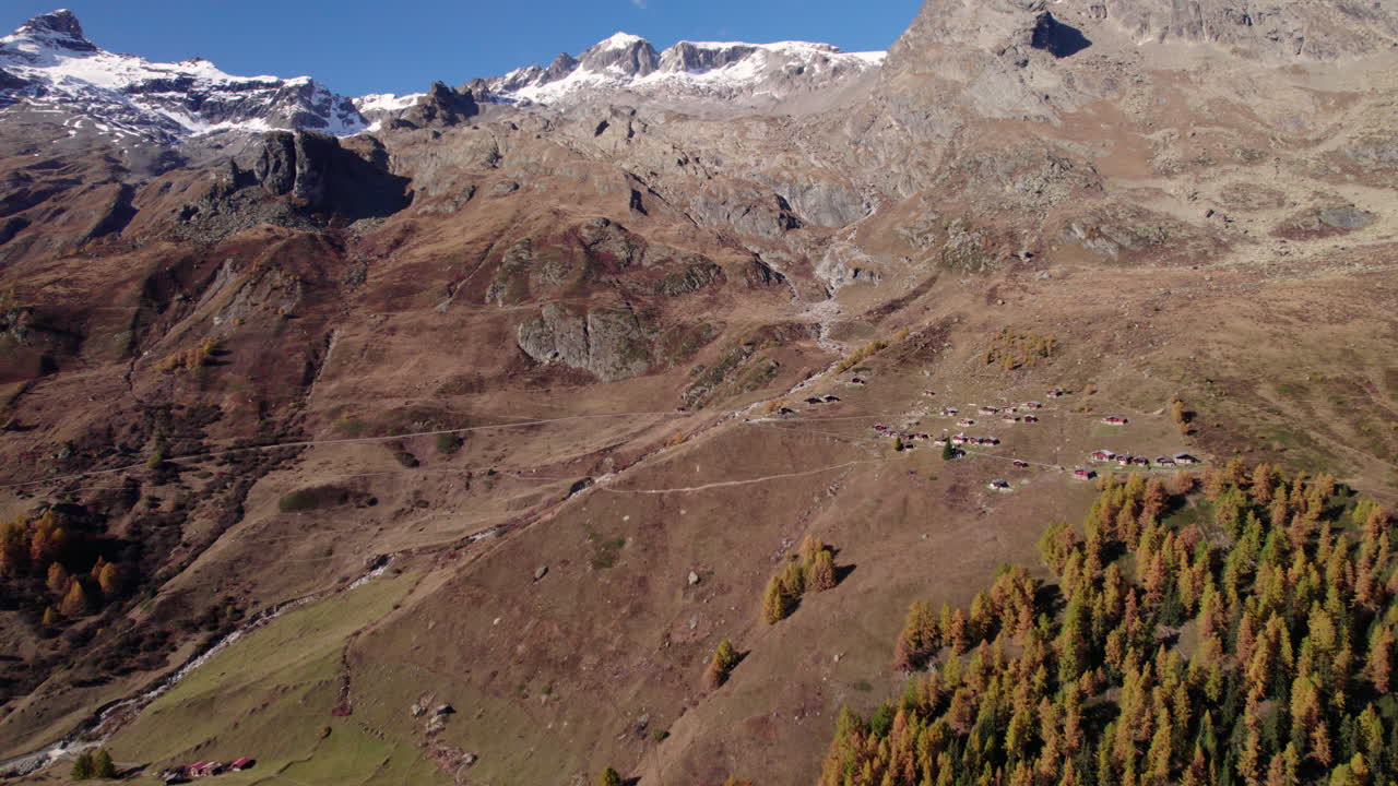 Drone shot of a mountain with yellow conifer trees in autumn, Lötschental, Switzerland