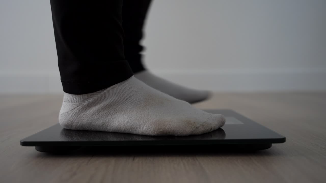 Nervous pregnant woman shifting feet on scale in last weeks of pregnancy